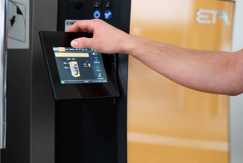 Eine Person bedient über einen Touchscreen die Steuerung einer modernen Heizungsanlage der Marke ETA.