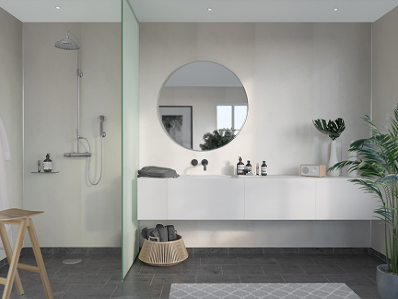 Modernes Badezimmer mit offener Regendusche, rundem Spiegel und schwebendem Waschtisch aus der Kollektion Legato Adagio. Elegantes Design mit schwarzen Armaturen, grauen Bodenfliesen und stilvollen Deko-Elementen wie Pflanzen und Badaccessoires.