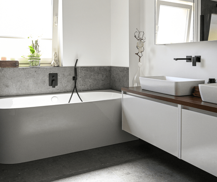 Badezimmer mit Badewanne und einen Badezimmertisch mit zwei Waschbäcken inkl. Armaturen