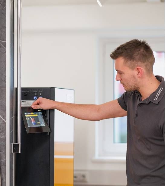 Ein Techniker bedient über einen Touchscreen die Steuerung einer modernen Heizungsanlage.