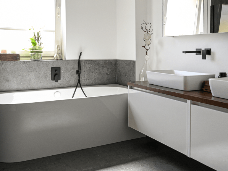 Badezimmer mit Badewanne und einen Badezimmertisch mit zwei Waschbäcken inkl. Armaturen