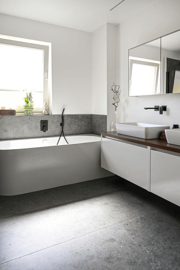 Badezimmer mit Badewanne und einen Badezimmertisch mit zwei Waschbäcken inkl. Armaturen